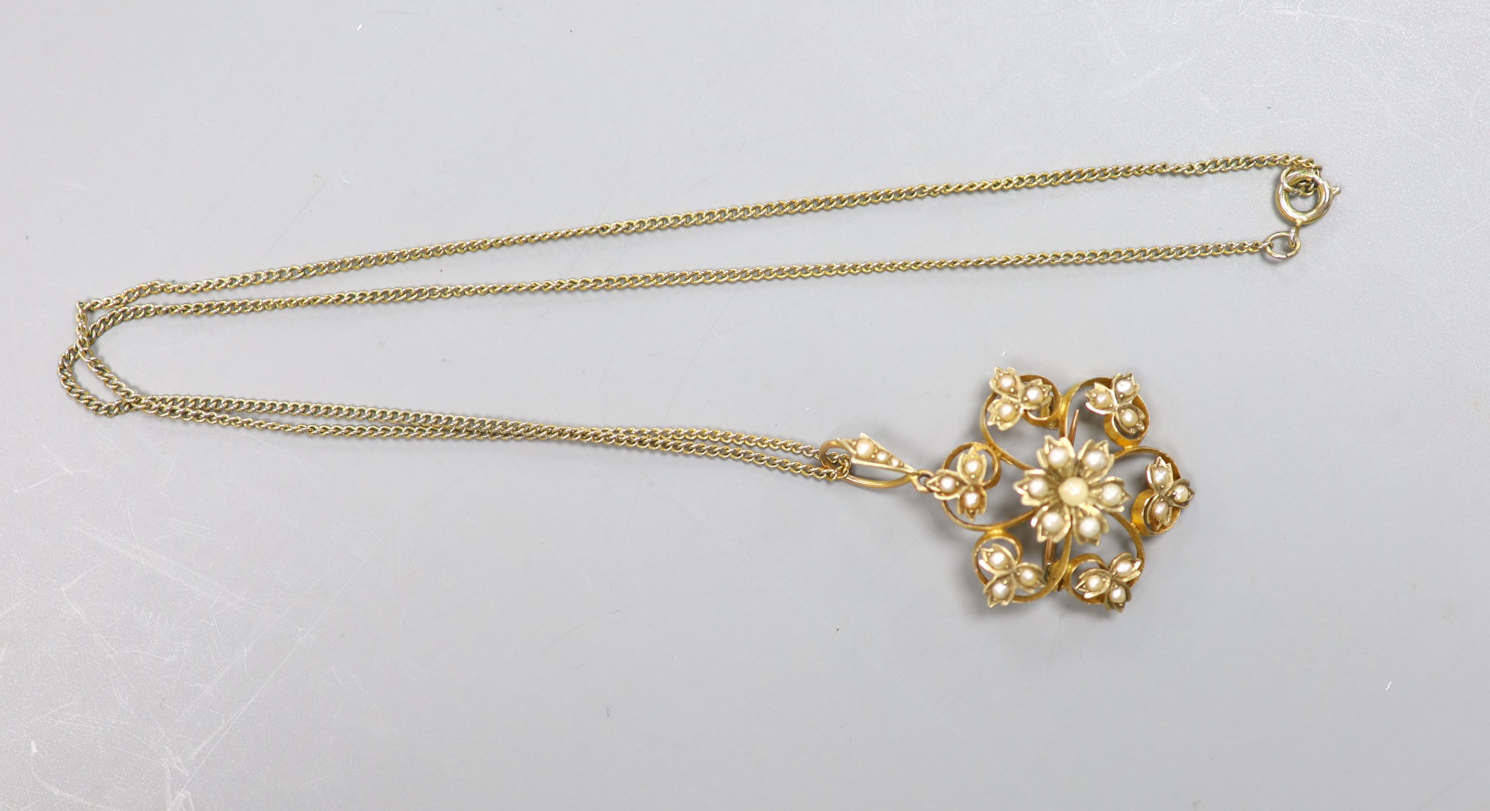 An Edwardian yellow metal and seed pearl set flower head pendant brooch